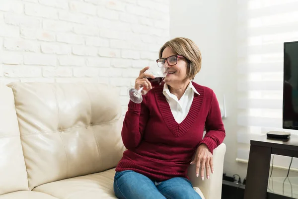 Wanita Tua Tersenyum Sambil Minum Anggur Merah Sambil Duduk Sofa — Stok Foto