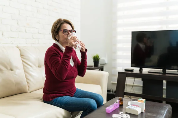 Senior Woman Užívat Pilulku Zatímco Sedí Pohovce Obývacím Pokoji — Stock fotografie