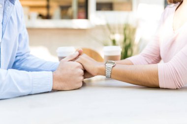 Kaldırımdaki kafede el ele tutuşan çiftlerin orta kesimi