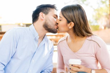 Romantic Hispanic boyfriend kissing girlfriend during date at cafe