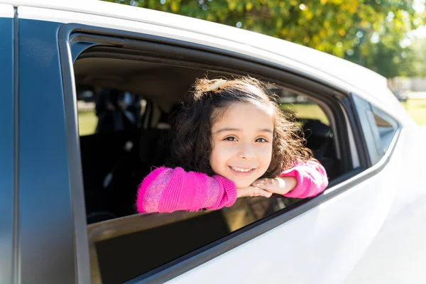 Smiling Girl Leaning On Car Window While Making Eye Contact During Sunny Day
