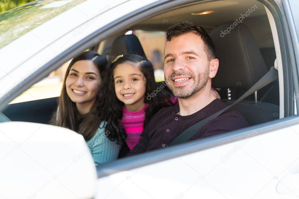 Smiling Parents With Daughter Sitting In Car While Making Eye Contact During Weekend