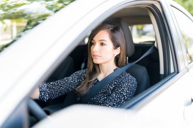 Confident beautiful woman driving new car seen through window