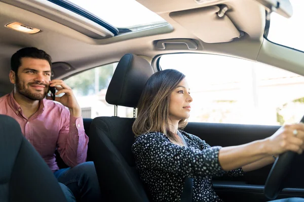 自信的女司机驾驶出租车 而男乘客在车上使用手机 — 图库照片