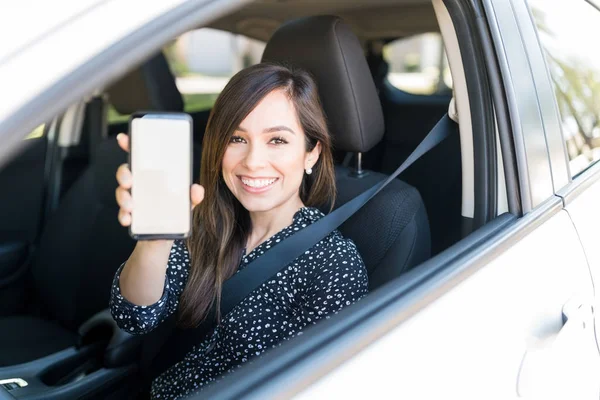 新しい車の中で座っている間にスマートフォンを示す幸せな大人の女性 — ストック写真