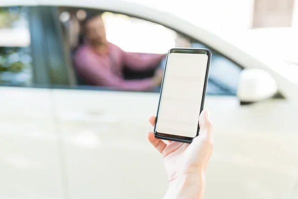 車に対して空白の画面を持つ携帯電話を使用して大人の女性の作物の手 — ストック写真
