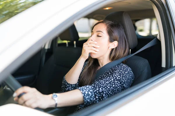 Bored woman yawning while waiting in car during traffic