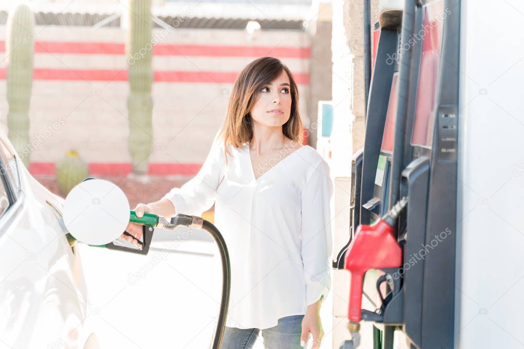 Mid adult woman refueling car at self-service gas station