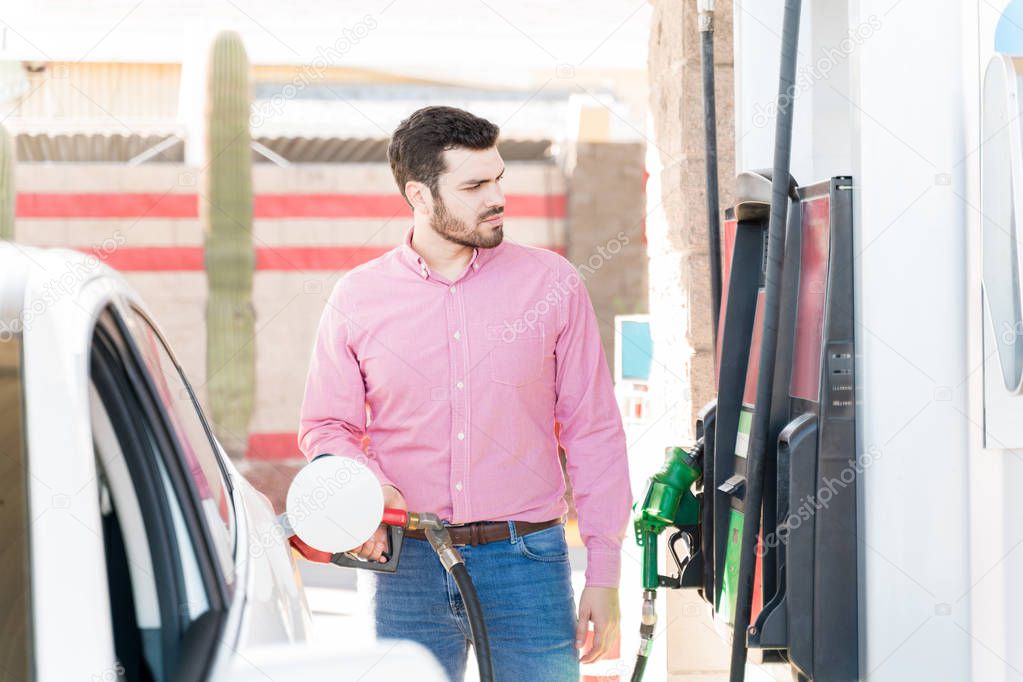 Hispanic man in casual refueling car at self-service gas station