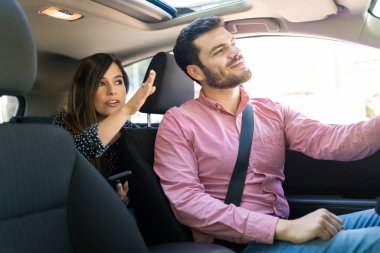 Orta yaşlı kadın kendine güvenen erkek taksi şoförüne yol gösteriyor.