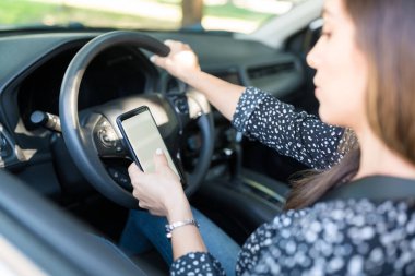 Female driver using mobile phone while sitting on driver's seat in car