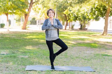 Yaşlı, beyaz bir kadının yoga pozu veren portresi.