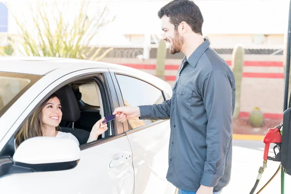 ガソリンスタンドで車に座っている間にクレジットカードで支払う笑顔の女性 — ストック写真