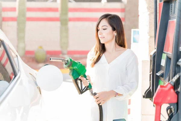 自给加油站的妇女开车拿着燃油喷嘴 — 图库照片
