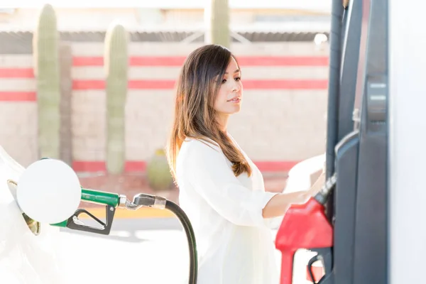 ガソリンスタンドで燃料ポンプ機を運転する笑顔の女性 — ストック写真