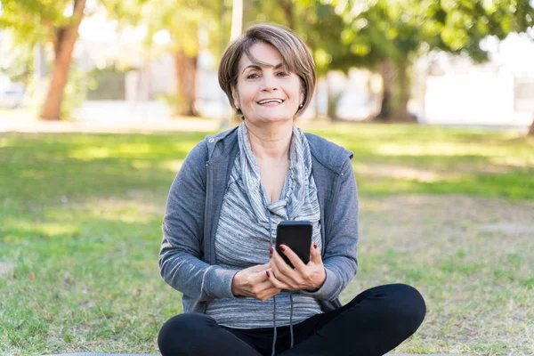 Lächelnde Ältere Kaukasierin Sitzt Mit Smartphone Park Und Nimmt Blickkontakt — Stockfoto