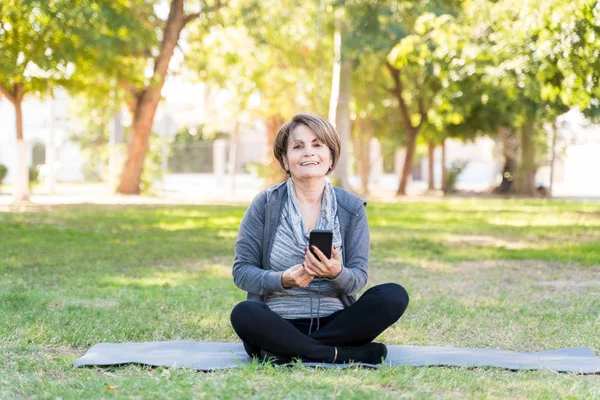 Retrato Mulher Idosa Aposentada Feliz Segurando Telefone Celular Enquanto Sentado — Fotografia de Stock