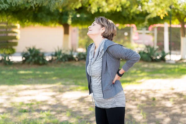 Senior Woman Hand Back Grimacing Pain While Standing Park — Stock Photo, Image