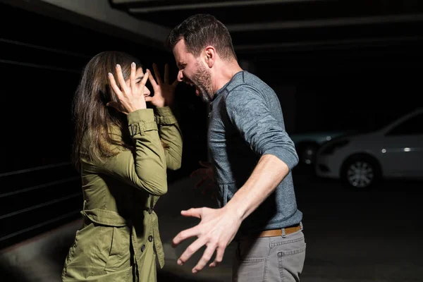 Side view of angry couple showing aggression while quarreling in dark parking lot