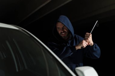 Kapüşonlu İspanyol haydut karanlık otoparkta arabanın camına levyeyle vurdu.