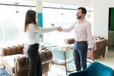 Görevdeki yeni erkek çalışanı selamlarken kadın işveren el sıkışıyor.