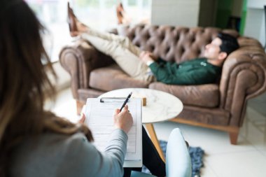 Ofiste tedavi sırasında erkeklerle tartışan psikolog not defterine yazıyor. 