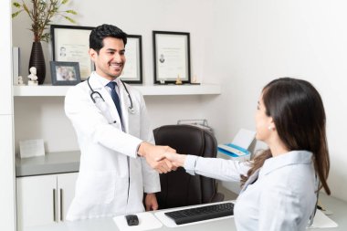 Hastaneye gelen kadın erkek doktorla el sıkışıyor.
