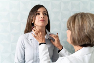 Beyaz kadın tiroit kontrolü için kadın aile doktorunu ziyaret ediyor.
