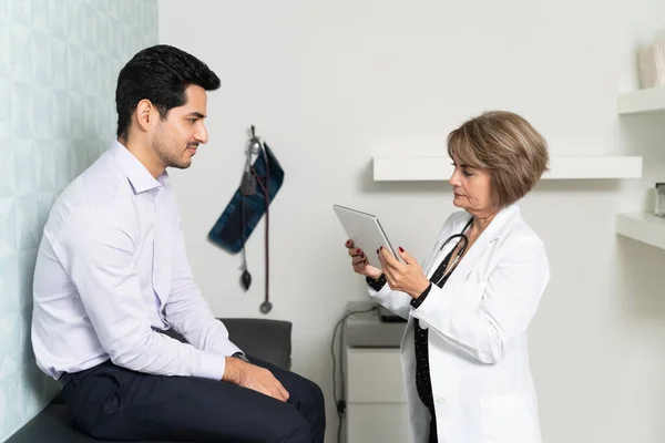 Médica Sênior Examinando Prontuário Eletrônico Enquanto Paciente Sentado Clínica — Fotografia de Stock