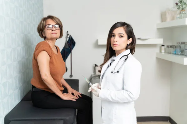 自信のある白人女性Geriatricianとともに注射器によってシニア患者座って試験表 — ストック写真