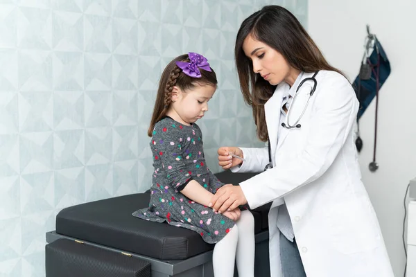 自信的女儿科医生用胶布包扎坐在手术台上的可爱女孩 — 图库照片