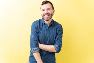 Sarı arka planda rahat duran kendine güvenen Latin adam.