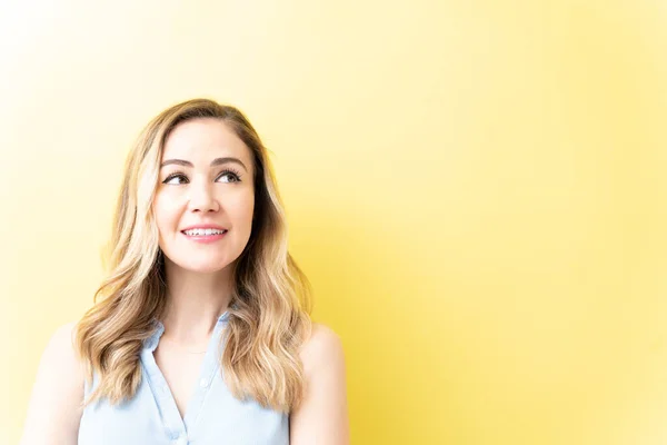 Feliz Mujer Bonita Reflexiva Mirando Hacia Arriba Contra Fondo Amarillo —  Fotos de Stock