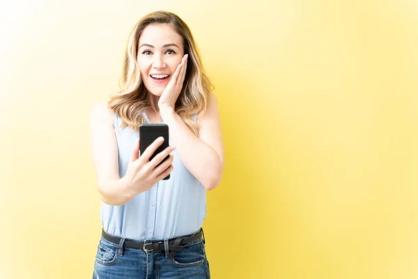 Feliz Surpreendido Mulher Caucasiana Segurando Smartphone Contra Fundo Amarelo — Fotografia de Stock