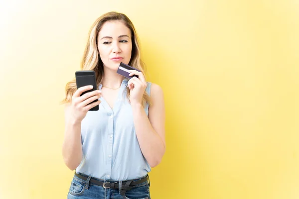 白人妇女在黄色背景下通过智能手机购物时使用信用卡 — 图库照片