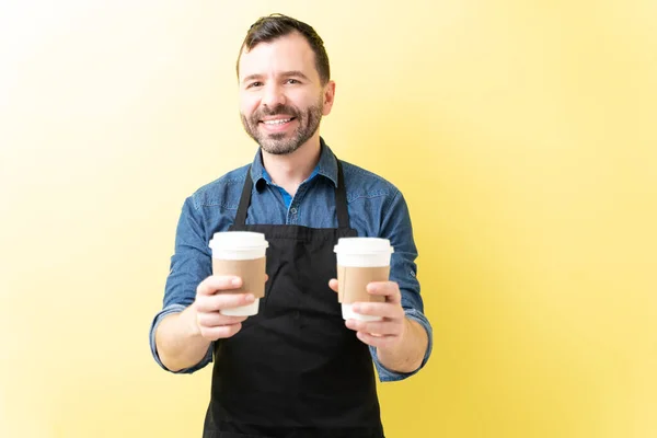 自信的男性咖啡师 手持黄色背景的一次性咖啡杯 — 图库照片