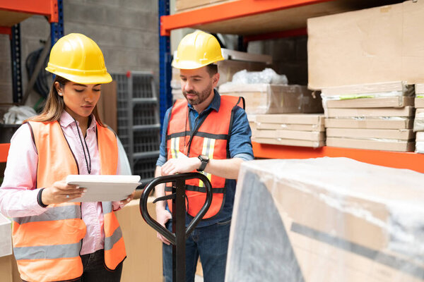 Коллеги по складу латинских женщин и мужчин обсуждают инвентаризацию
