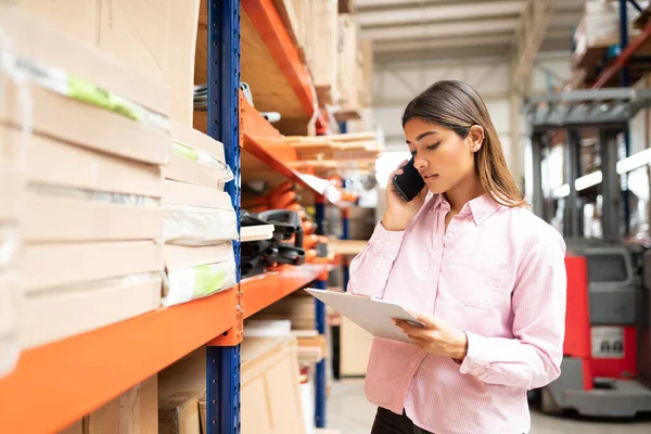 Joven Supervisor Hispano Hablando Smartphone Mientras Examina Inventario Por Rack —  Fotos de Stock