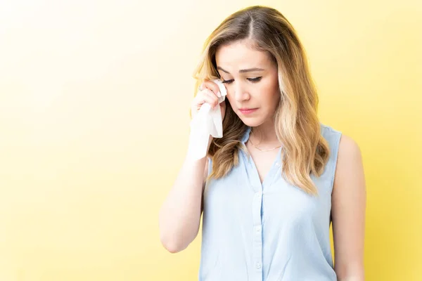 沮丧的白人女人用餐巾擦拭黄色背景的泪水 — 图库照片