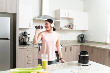 Muhteşem kadın mutfakta şarkı söylerken ve müzik dinlerken eğleniyor.