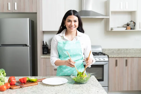 Gülümseyen Çekici Hanımı Kaşıklarla Salatayı Karıştırırken Mutfakta Göz Teması Kuruyor — Stok fotoğraf