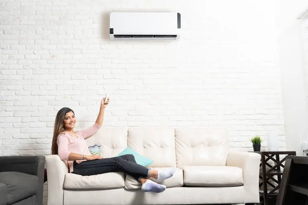 Smiling Hispanic Young Woman Adjusting Temperature Air Conditioner While Sitting — Stock Photo, Image