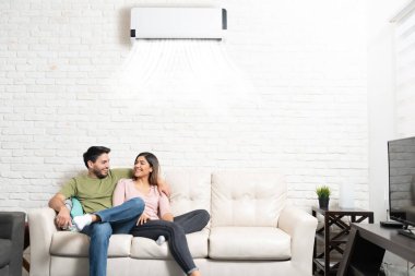 Mutlu Latin sevgili ve kız arkadaş evdeki oturma odasında klimalı kanepede dinleniyor.