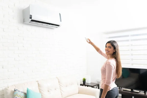 Hispanic Söt Kvinna Slå Luftkonditionering Med Hjälp Fjärrkontroll Vardagsrummet Hemma — Stockfoto