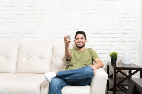 Smiling Handsome Latin Man Using Air Conditioner Remote Control While — Stock Photo, Image