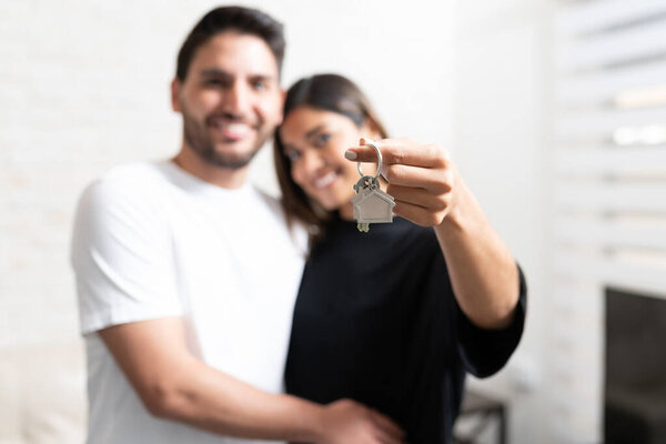 Smiling boyfriend with girlfriend showing key of new house while standing at home