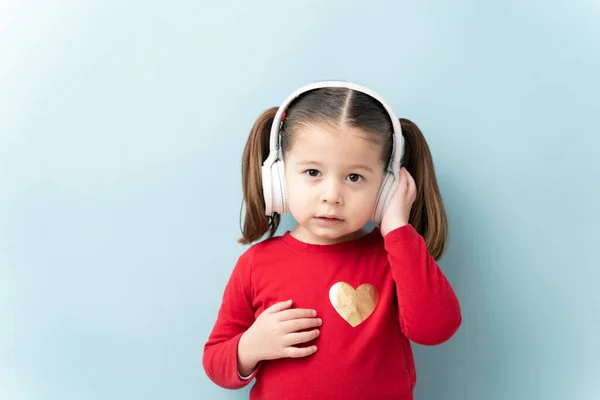 一个漂亮的小女孩在录音室里用无线耳机和复制空间听音乐的肖像 — 图库照片