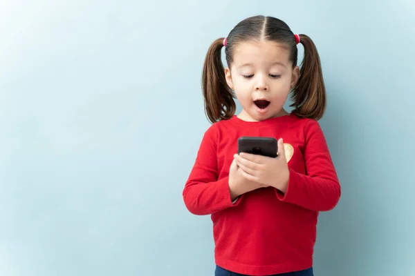 Cute Little Girl Holding Smartphone Looking Surprised Her Mouth Open — Stock Photo, Image