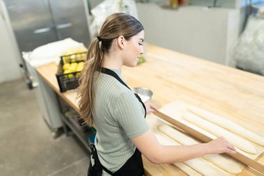 Fırında ekmek yapmak için hamur kesen genç bir fırıncının arka görüntüsü.