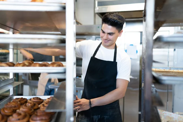 Hombre Hispano Guapo Disfrutando Trabajo Una Panadería Moviendo Estante Lleno — Foto de Stock